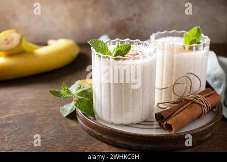 Menu Detox (disintossicazione). Frullato alla banana con cannella in bicchiere su sfondo di legno. Copia spazio. Foto Stock