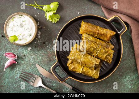 Delizioso dolma - foglie d'uva ripiene con riso e carne su sfondo di pietra scura. Greco tradizionale, caucasico e turco c Foto Stock