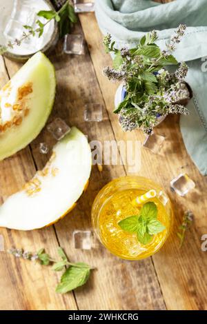 Limonata di melone in bicchieri con ghiaccio e menta su un tavolo rustico in legno. Bevanda estiva fresca e fruttata, bevande di stagione. Foto Stock