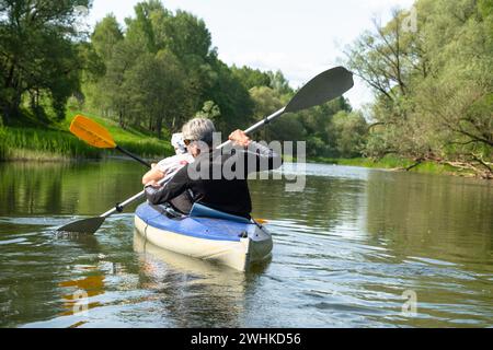 Gita in kayak per tutta la famiglia per il Seigneur e senora. Una coppia di anziani sposati che voga una barca sul fiume, un'escursione in acqua, un avventuriero estivo Foto Stock