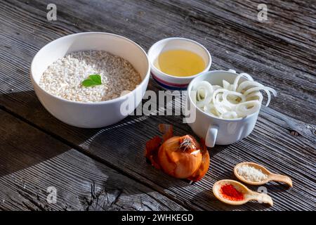 Ingrediente crudo per preparare il riso allo zafferano, il risotto alla milanese con parmigiano, vino bianco e cipolla e una foglia a forma di cuore su un legno antico Foto Stock