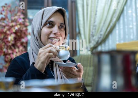 Donna che beve caffè con la faccia sorridente Foto Stock