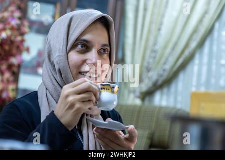 Donna che beve caffè con la faccia sorridente Foto Stock