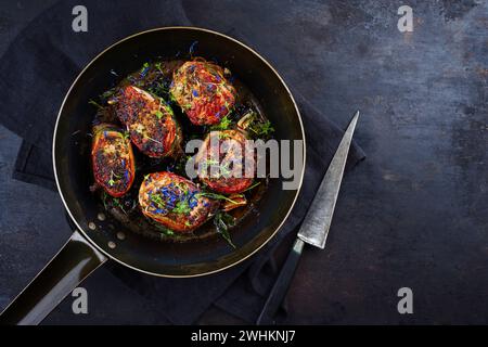 Tradizionali medaglioni di filetto di vitello arrosto con rivestimento di pancetta e foglie di salvia in salsa di burro serviti come vista dall'alto su un battuto rustico Foto Stock