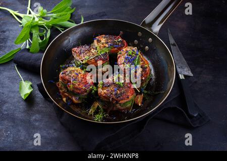 Tradizionali medaglioni di filetto di vitello arrosto con rivestimento di pancetta e foglie di salvia in salsa di burro serviti da vicino su un battuto rustico Foto Stock