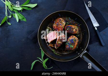 Tradizionali medaglioni di filetto di vitello arrosto con rivestimento di pancetta e foglie di salvia in salsa di burro serviti come vista dall'alto su un battuto rustico Foto Stock