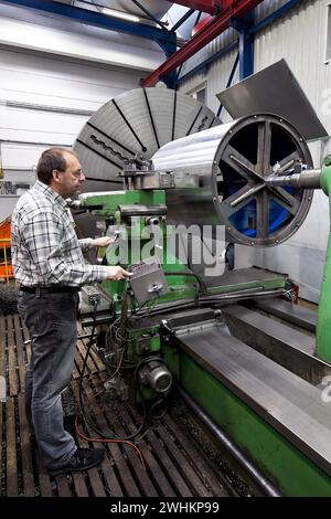 Lavoratore anziano nell'industria dei metalli presso una fresatrice CNC Foto Stock