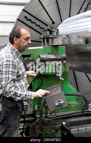 Lavoratore anziano nell'industria dei metalli presso una fresatrice CNC Foto Stock