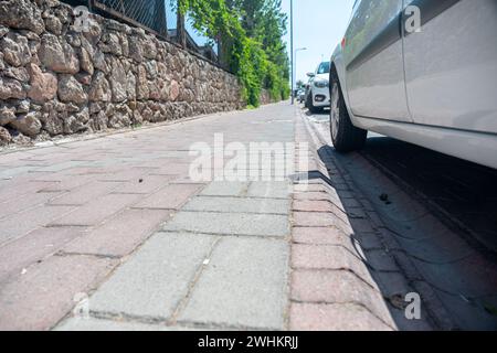 Marciapiede per i popoli in design moderno accanto ad alcune auto parcheggiate Foto Stock