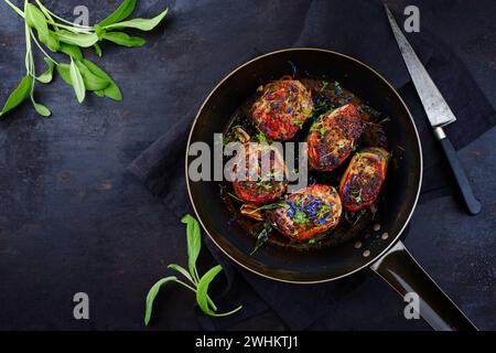 Tradizionali medaglioni di filetto di vitello arrosto con rivestimento di pancetta e foglie di salvia in salsa di burro serviti come vista dall'alto su un battuto rustico Foto Stock