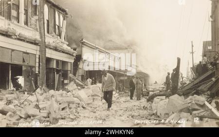 3 febbraio 1931. Napier, nuova Zelanda. Le persone nella strada coperte dall'edificio danneggiato del terremoto di Napier, mentre il fumo degli incendi in corso riempie il cielo. Foto Stock
