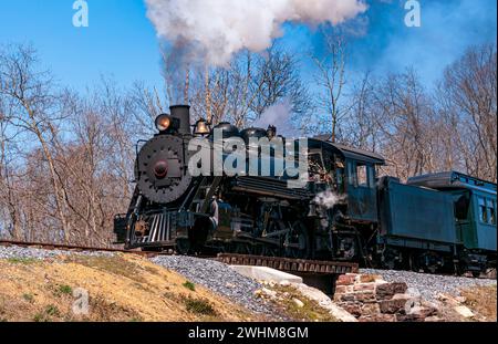 Vista leggermente più bassa di un treno a vapore passeggeri a scartamento ridotto restaurato che soffia fumo Foto Stock