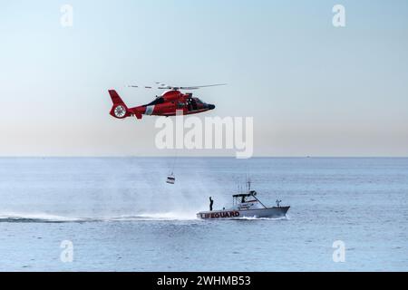 Los Angeles, California, Stati Uniti - 10 novembre 2023; elicottero della Guardia Costiera americana che abbassa un cesto su una barca di guardia della contea di Los Angeles. Foto Stock