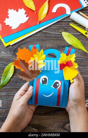 Zaino di carta per biglietti d'auguri su un tavolo di legno. Ritorno al concetto di scuola. Fatto a mano. Progetto di creatività per bambini, artigianato per k Foto Stock