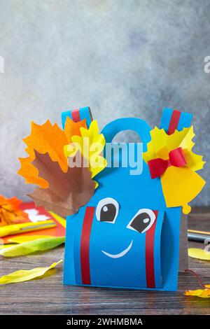 Ritorno al concetto di scuola. Zaino di carta per biglietti d'auguri su un tavolo di legno. Progetto di creatività per bambini, artigianato, mestieri, ecc. Foto Stock