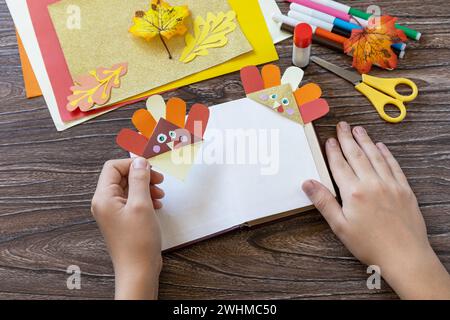 Nelle mani di un bambino Thanksgiving mestiere segnalibro carta tacchino. Progetto d'arte per bambini, fatto a mano, artigianato per bambini. Foto Stock