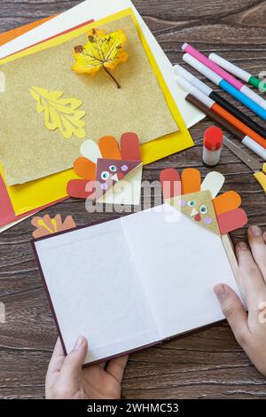 Nelle mani di un bambino Thanksgiving mestiere segnalibro carta tacchino. Progetto d'arte per bambini, fatto a mano, artigianato per bambini. Foto Stock