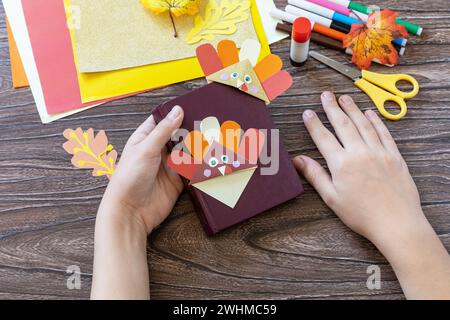 Nelle mani di un bambino Thanksgiving mestiere segnalibro carta tacchino. Progetto d'arte per bambini, fatto a mano, artigianato per bambini. Foto Stock