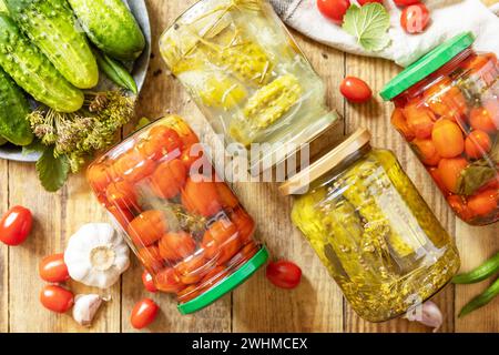 Cetrioli sottaceto salati e pomodori conservati in scatola in vaso di vetro. Economia domestica, conservazione del raccolto autunnale. Omema sano Foto Stock