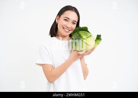 Bella donna sorridente, tenendo cavolo, posando con lattuga su sfondo bianco Foto Stock