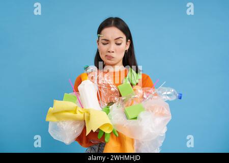 Cura della natura. Giovane donna che tiene bottiglie di plastica e rifiuti. I volontari hanno compilato la spazzatura e la portano al riciclaggio. il blu è Foto Stock