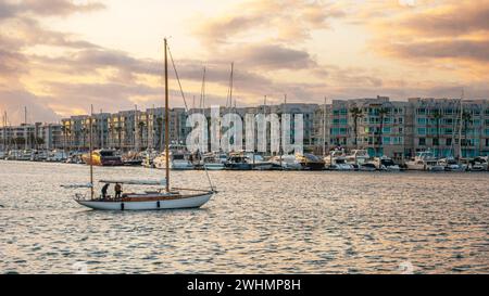 Persone che navigano attraverso Marina del Rey, California, al tramonto su una barca a vela Foto Stock