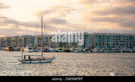 Persone che navigano attraverso Marina del Rey, California, al tramonto su una barca a vela Foto Stock