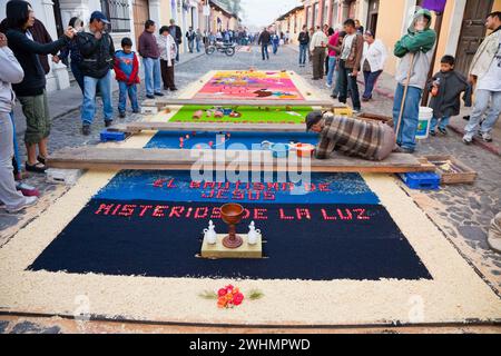 Antigua, Guatemala. Preparare un alfombra (tappeto) di fiori, aghi di pino e altri materiali tradizionali per decorare la strada prima del Foto Stock