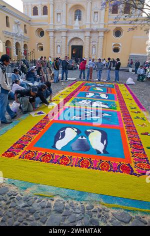 Antigua, Guatemala. Finalizzazione di un bordo di farfalle stencizzate su un alfombra (tappeto) di segatura colorata raffigurante temi ambientali che decorano Foto Stock