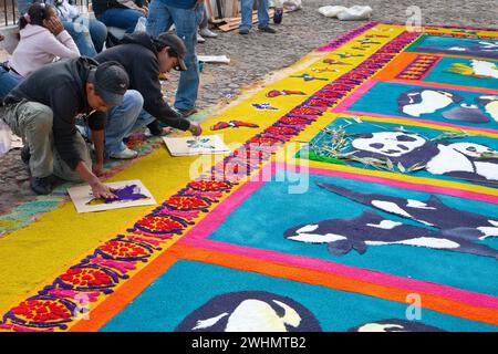 Antigua, Guatemala. Finalizzare una farfalla stencizzata su un alfombra (tappeto) di segatura colorata raffigurante temi ambientali che decorano la strada Foto Stock