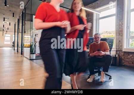 Un gruppo eterogeneo di professionisti collabora in un moderno centro di coworking startup, utilizzando un mix di supporti cartacei e. Foto Stock