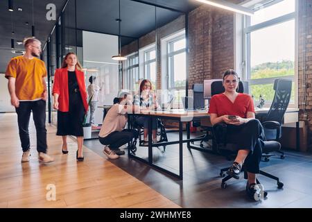 Un gruppo eterogeneo di professionisti collabora in un moderno centro di coworking startup, utilizzando un mix di supporti cartacei e. Foto Stock