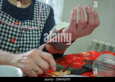 Una signora anziana che controlla i suoi livelli di pressione sanguigna a casa Foto Stock