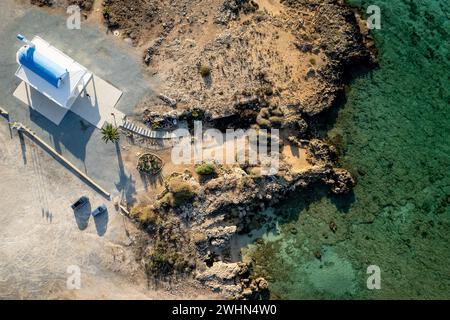 Costa rocciosa aerea con droni e cappella cristiana bianca. Vista dall'alto del mare con acqua turchese. Chiesa di Ayia thekla Ayia Napa Cipro Foto Stock