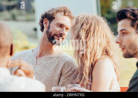 Concetto di stile di vita di una bella giovane coppia innamorata che si separa dal loro gruppo di amici sullo sfondo per una vacanza all'aria aperta Foto Stock