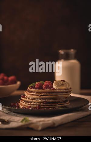 Pancake con lamponi, fette di banana, semi di melograno e miele Foto Stock