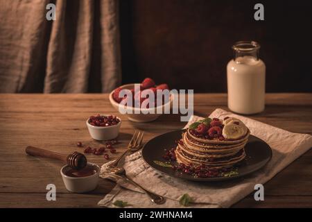 Pancake con lamponi, fette di banana, semi di melograno e miele Foto Stock