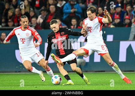 Leverkusen, Germania. 10 febbraio 2024. Florian Wirtz (C) del Bayer 04 Leverkusen vies con Leroy sane (L) e Leon Goretzka del Bayern Monaco durante la partita di prima divisione della Bundesliga tra Bayer 04 Leverkusen e Bayern Monaco di Baviera a Leverkusen, Germania, 10 febbraio 2024. Crediti: Ulrich Hufnagel/Xinhua/Alamy Live News Foto Stock