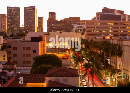 Vista al crepuscolo del traffico che scorre lungo Rodeo Drive con lo skyline del centro storico di Beverly Hills, California, Stati Uniti. Foto Stock