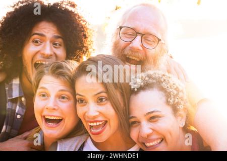 Momenti di gioia: Amici multirazziali abbracciano il tramonto in campagna Foto Stock