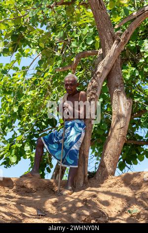 Il vecchio riposa all'ombra vicino a un traghetto che attraversa il fiume a Belo Sur Tsiribihina, Madagascar Foto Stock