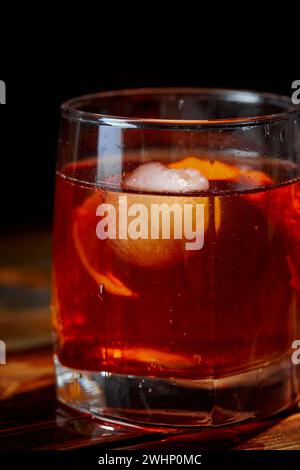 Cocktail alcolico Negroni o cocktail analcolico, bevanda con ghiaccio e scorza d'arancia come decorazione su tavolo di legno Foto Stock