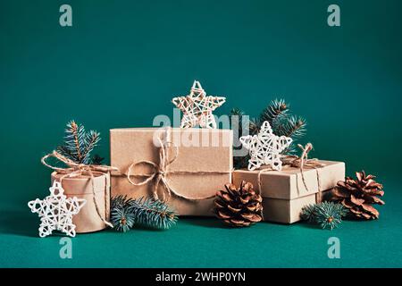 Composizione di scatole regalo natalizie sostenibili con decorazioni naturali su sfondo verde. Natale zero sprechi, giorno di pugilato e inverno Foto Stock