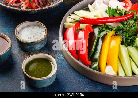 Piatto con verdure, peperoni, pomodori e verdure e vari tipi di salse Foto Stock