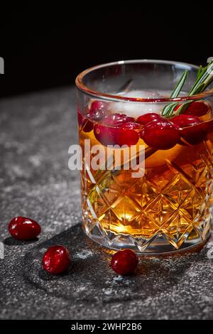 Bere con mirtilli rossi e rosmarino, whisky, tequila o cognac, limonata, cocktail alcolici o analcolici su un tavolo scuro Foto Stock