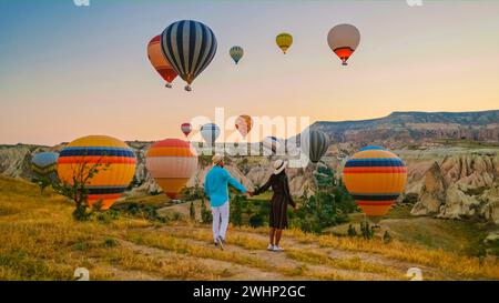 Felice giovane coppia durante l'alba guardando le mongolfiere di Kapadokya Cappadocia Turchia Foto Stock