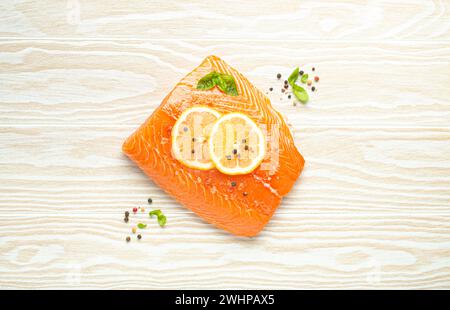 Filetto di salmone crudo fresco marmorizzato su fondo bianco rustico da tavola in legno con limone, sale grosso, erbe verdi vista dall'alto. Sano c Foto Stock