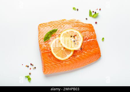 Filetto di salmone crudo fresco marmorizzato isolato su sfondo bianco con limone, sale grosso, erbe verdi vista dall'alto. Nutrizione sana AN Foto Stock