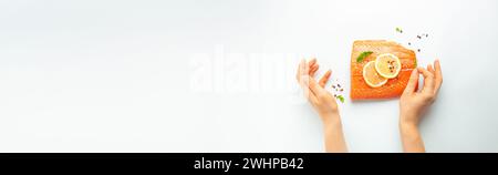 Condimento delle mani delle donne filetto di salmone fresco crudo marmorizzato isolato su sfondo bianco con limone, sale grosso, erbe verdi top vie Foto Stock