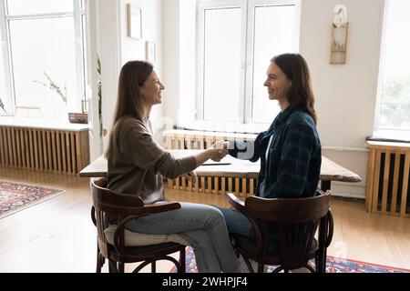 Due allegre imprenditrici che stringono la mano al tavolo da lavoro Foto Stock